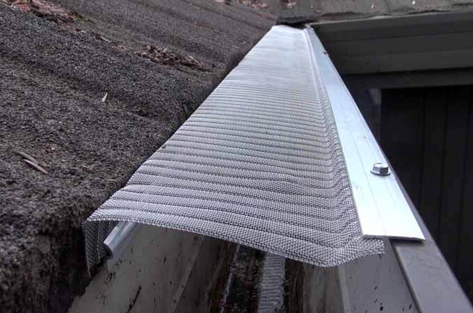 A close-up view of a stainless steel micro-mesh gutter guard installed along the edge of a roof, designed to prevent debris from entering the rain gutter.